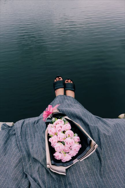 Chic outfit with bouquet of roses by serene lake view. Perfect combination of fashion and nature.