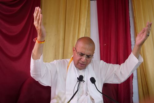 Free A religious figure in white clothing prays with raised arms during a spiritual gathering. Stock Photo