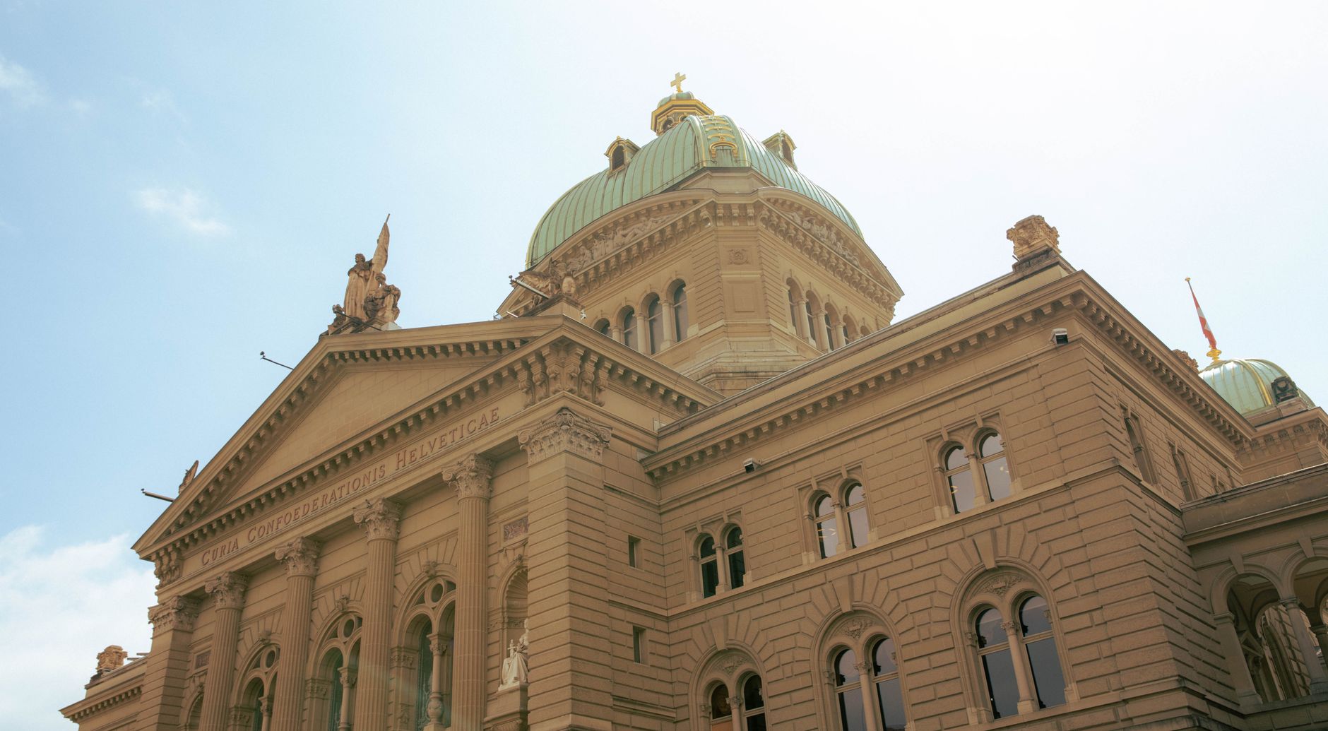 Low angle view of the Swiss Federal Palace in Berne, showcasing its ornate architecture on a sunny day.