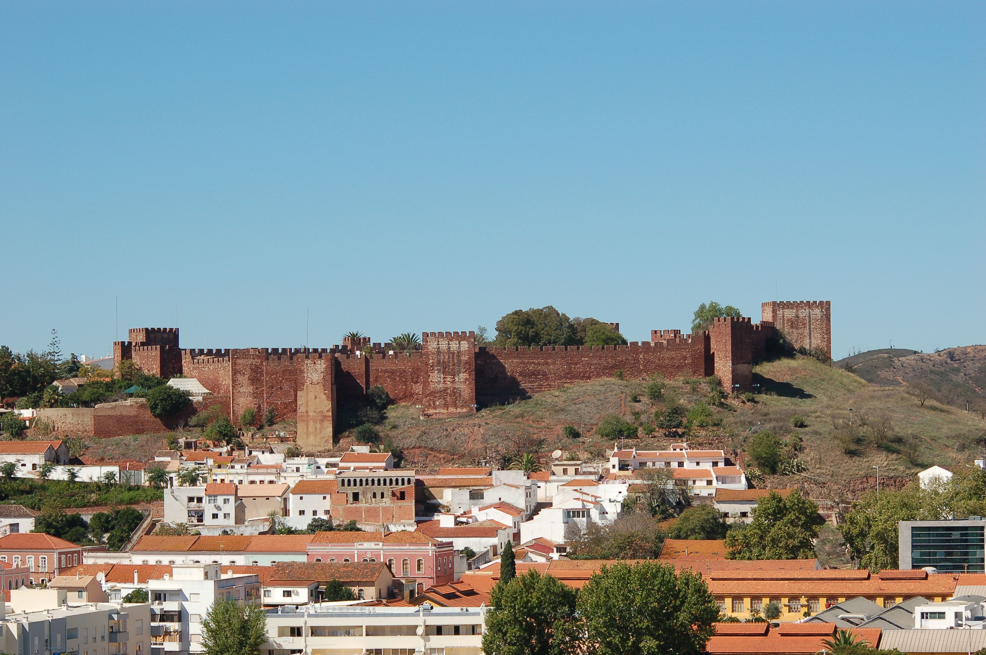 Scenic view of Silves Castle in Faro, Portugal, atop a hill with a town below.