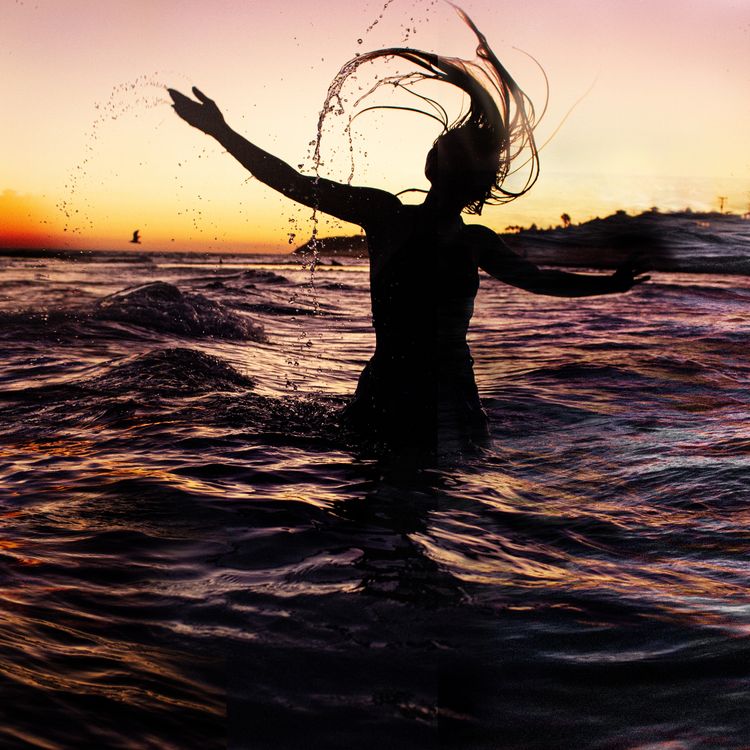A Woman Standing in Water at Sunset · Free Stock Photo