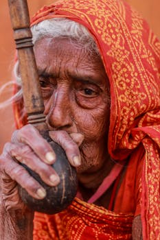 一位年长妇女的肖像，她戴着传统红围巾，手持手杖