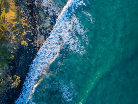 A breathtaking aerial view showcasing turquoise ocean waves crashing against a rocky shoreline.