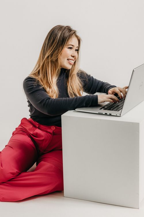 Free Smiling woman in casual attire using laptop indoors, creating a warm and professional look. Stock Photo
