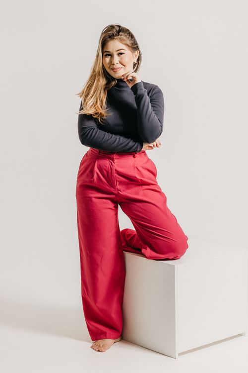 Free A woman poses confidently in a studio wearing fashion-forward red trousers. Stock Photo
