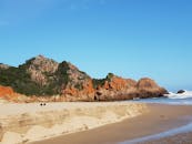 在晴朗的蓝天下，探索令人惊叹的海滩，那里的岩石悬崖呈现出橙色