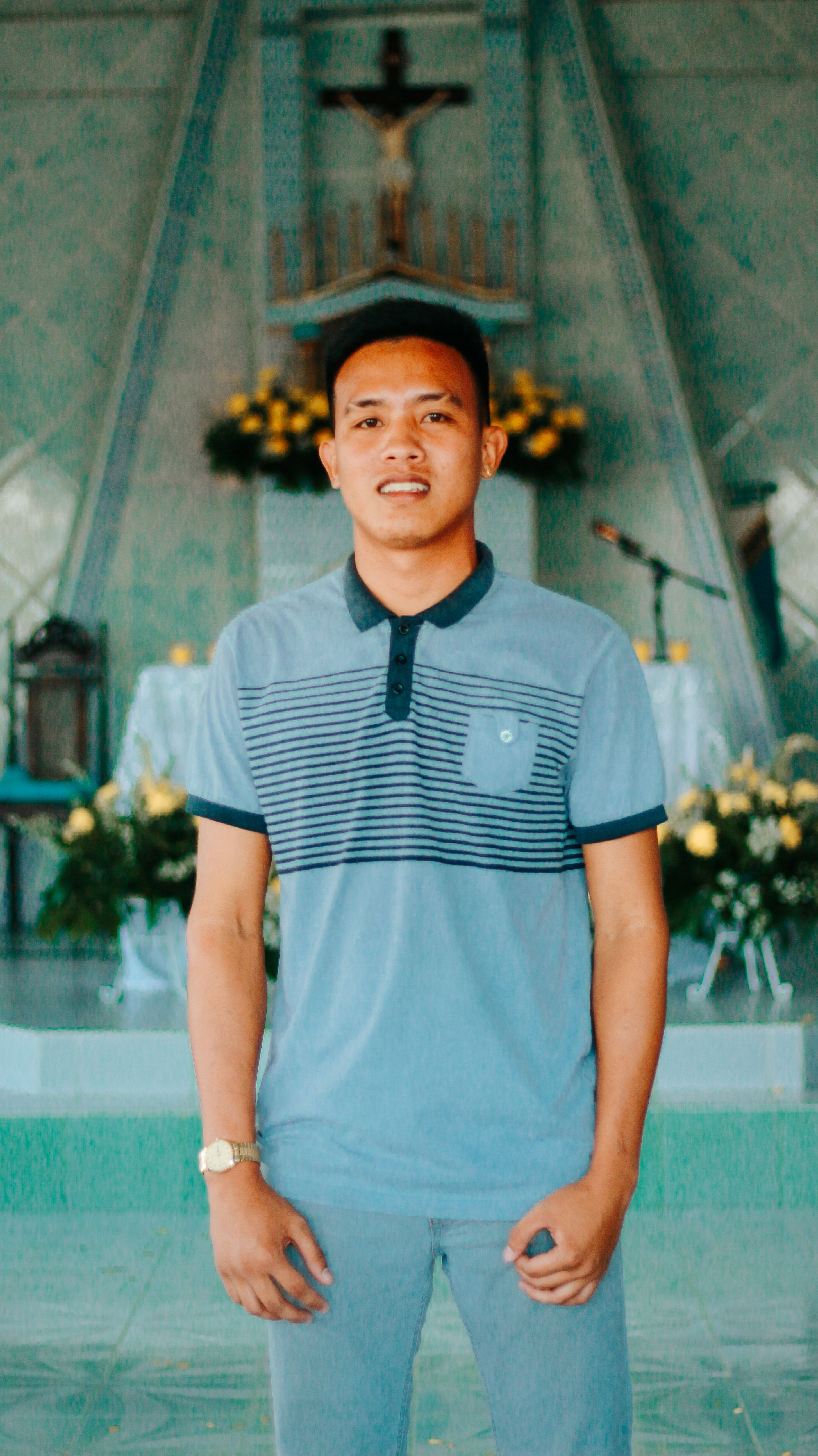 Portrait of a young man in a church, smiling and standing in front of a decorated altar.