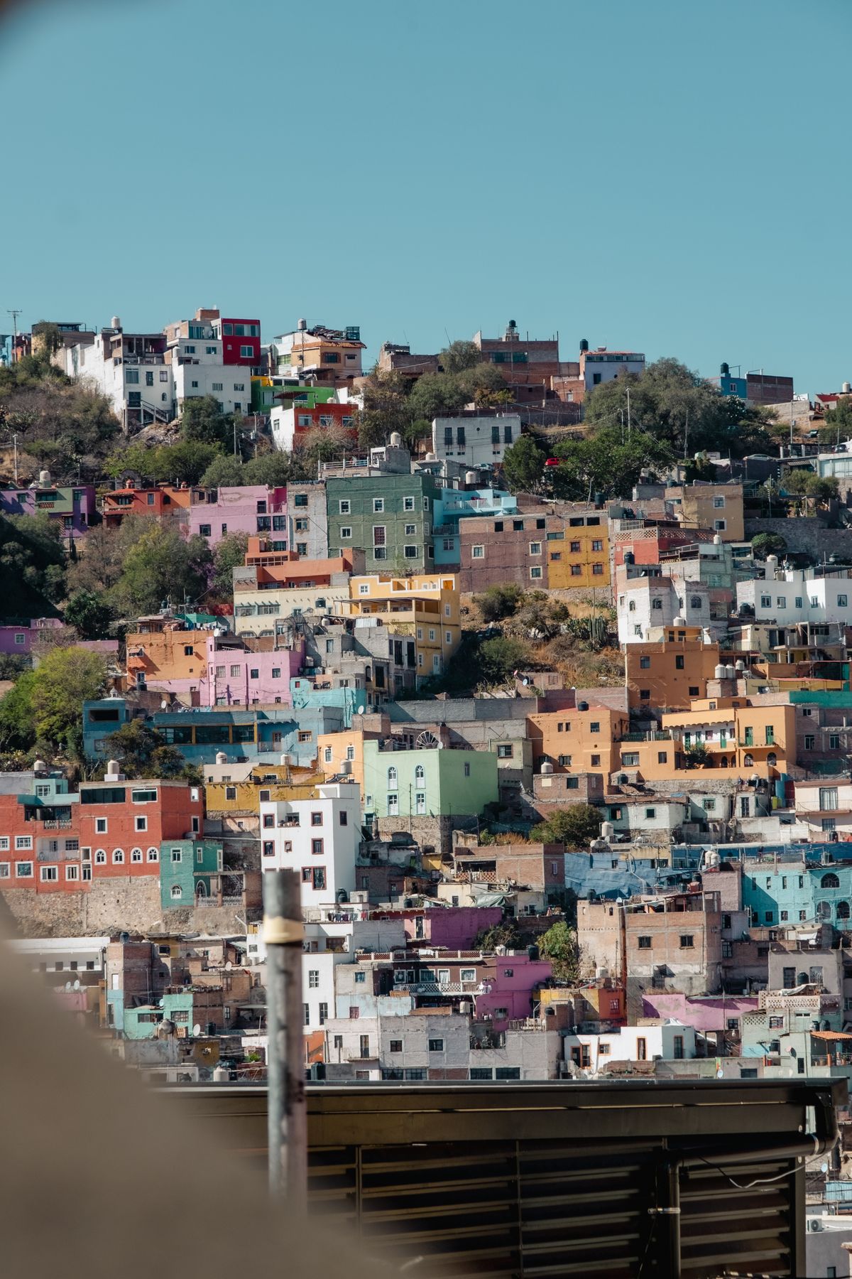 Vibrant, multicolored hillside buildings in Guanajuato, Mexico, under clear skies.