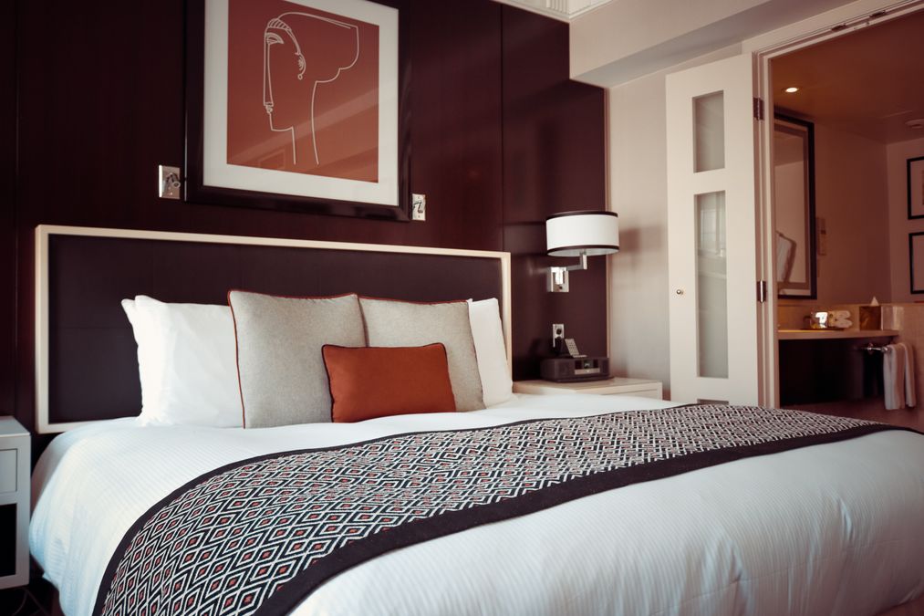 Hotel room bed with grey bedspread and pillows