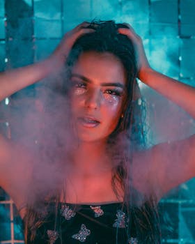 Mesmerizing portrait of a young woman with glitter makeup, posing amidst colorful steam in a studio.