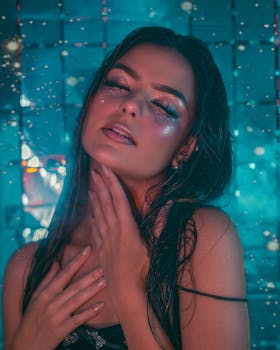Striking portrait of a young woman adorned with glitter makeup, against a shimmering background, creating a dreamy atmosphere.