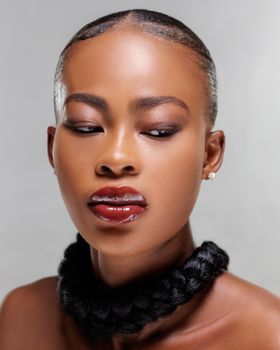 Close-up portrait of a stylish woman with bold makeup and slicked hairstyle, showcasing fashion and beauty.