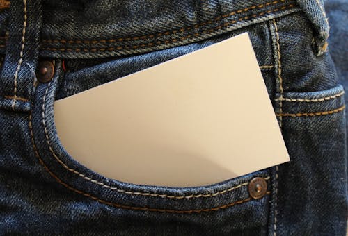 Белая карточка на сумочке из серых джинсовых брюк