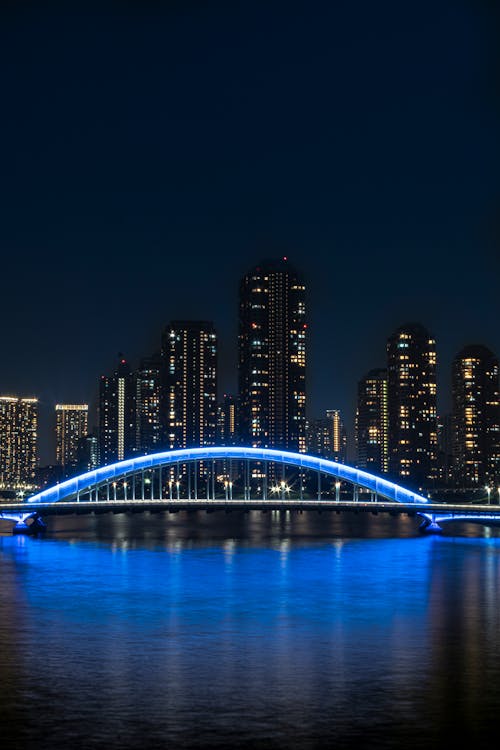Illuminated Bridge above River in City at Night