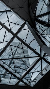 Dramatic view of a modern skyscraper through an intricate glass ceiling structure.