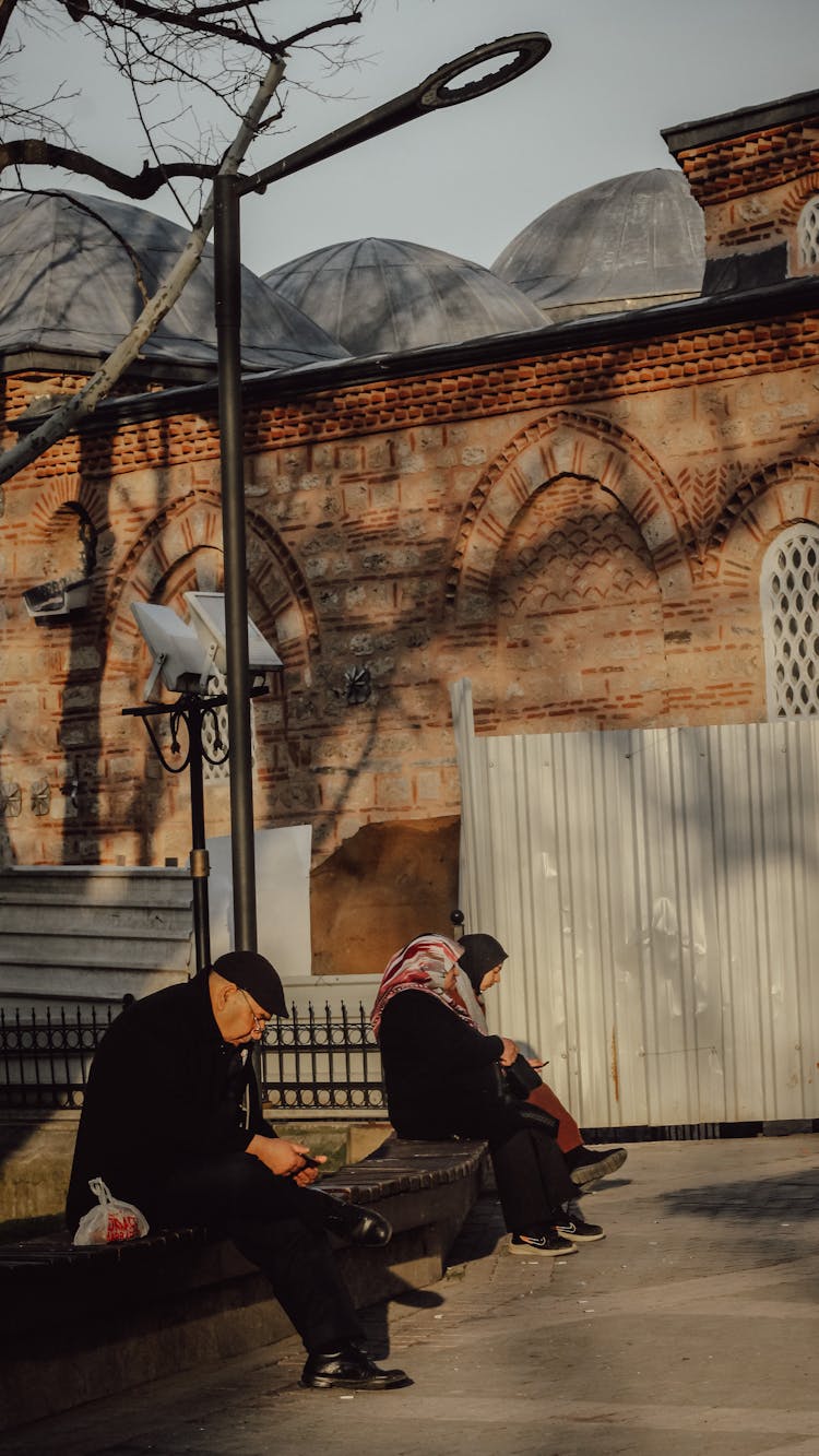 Elderly People On A Bench Next To The Building Under Renovation