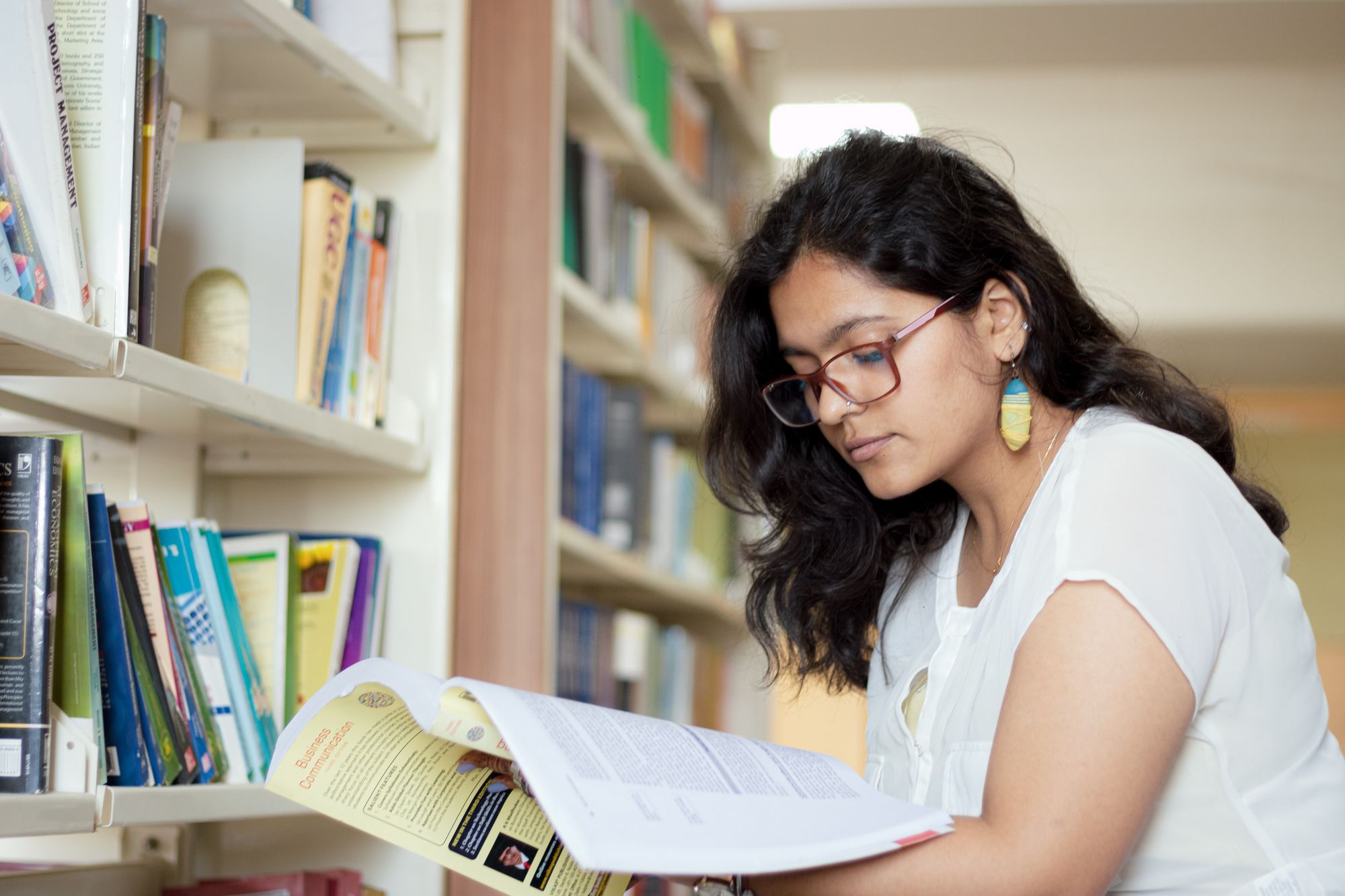A young student reading a book in a library in Delhi