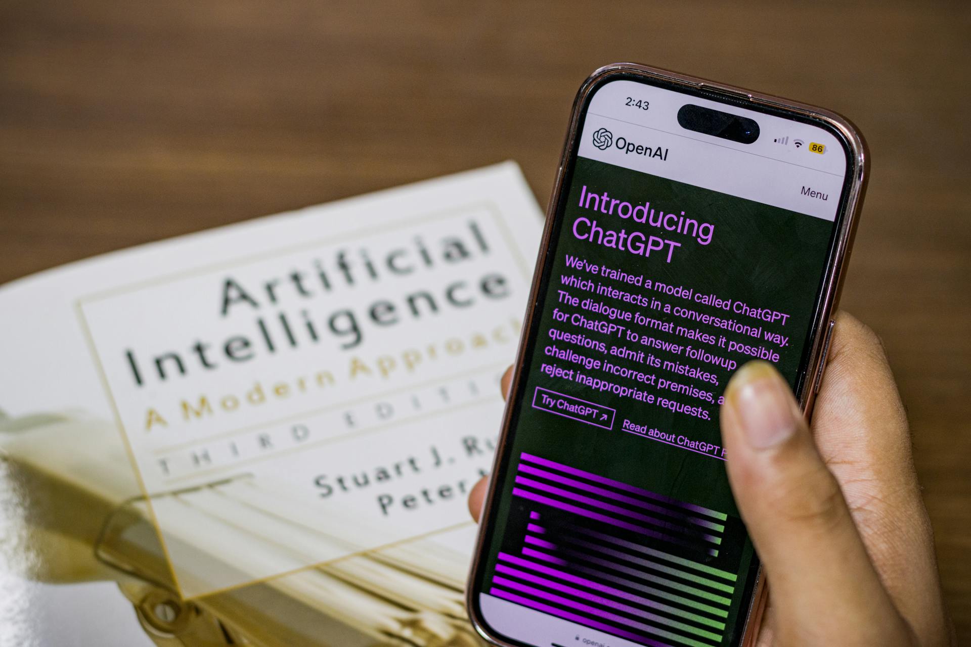 Close-up of a smartphone displaying ChatGPT app held over AI textbook.