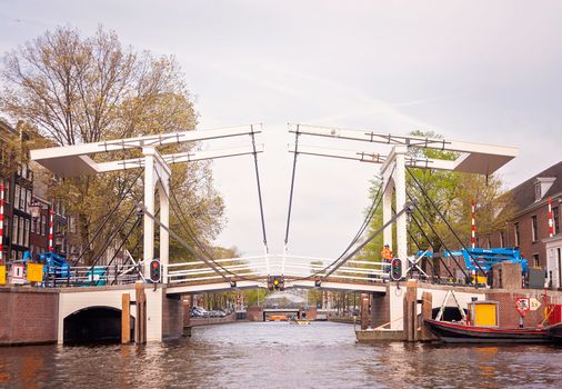 Scenic view of an Amsterdam drawbridge over a canal with urban surroundings.