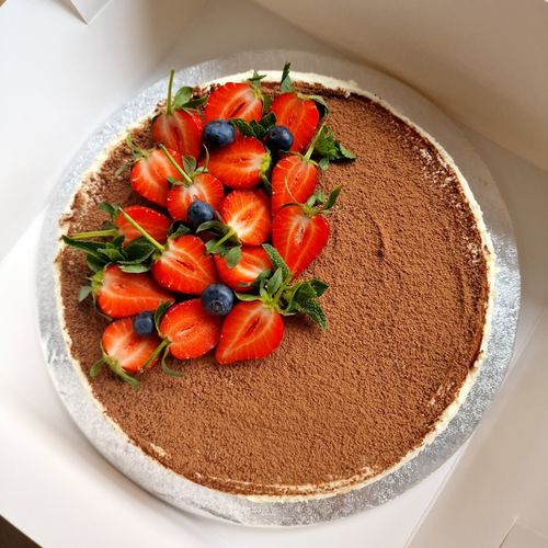 Free Top view of a tiramisu cake decorated with fresh strawberries and blueberries, perfect for dessert lovers. Stock Photo