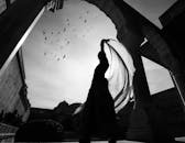 在历史悠久的拱门下，舞者的艺术轮廓与飘逸的织物，映衬着鸟儿的天空