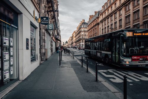 Free A bustling Paris street scene with a bus, historic buildings, and a quiet sidewalk atmosphere. Stock Photo