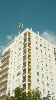 Vertical shot of a sunlit urban apartment building with blue sky background.
