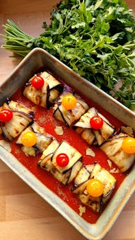 Delectable eggplant rolls with cherry tomatoes and fresh herbs, baked and flavorful.