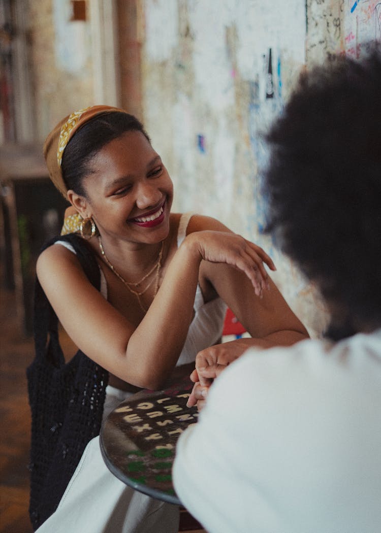 Young Man And Woman Sitting At A Table In A Cafe And Smiling 