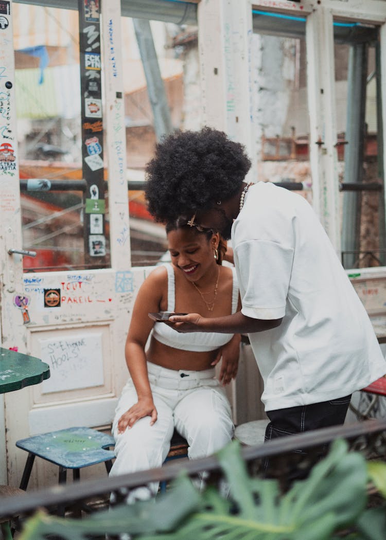 Young Man And Woman Looking At A Smartphone Screen And Smiling 