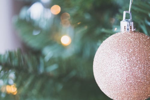 クリスマスツリーにぶら下がっている金の安物の宝石の浅い焦点の写真