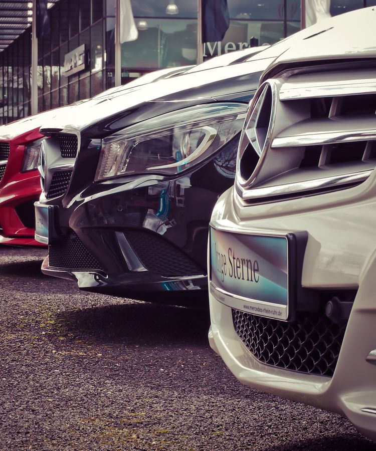 Luxury cars lined up at an outdoor dealership, showcasing sleek designs.
