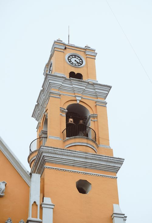 Free Vertical shot of an orange church clock tower in Xalapa-Enríquez, Mexico. Stock Photo