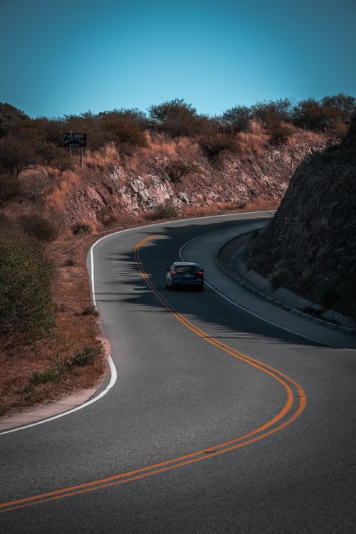 Free Car driving on a winding road through Argentine landscape, perfect for travel imagery. Stock Photo