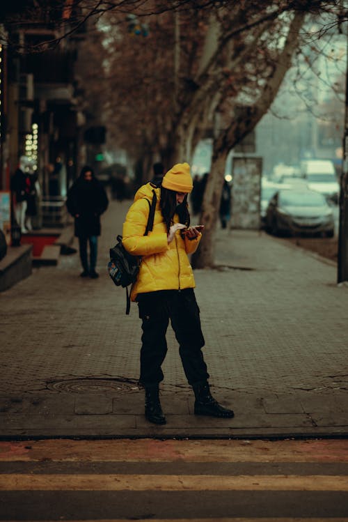 Young Woman Standing on the Sidewalk and Using her Smart Phone 