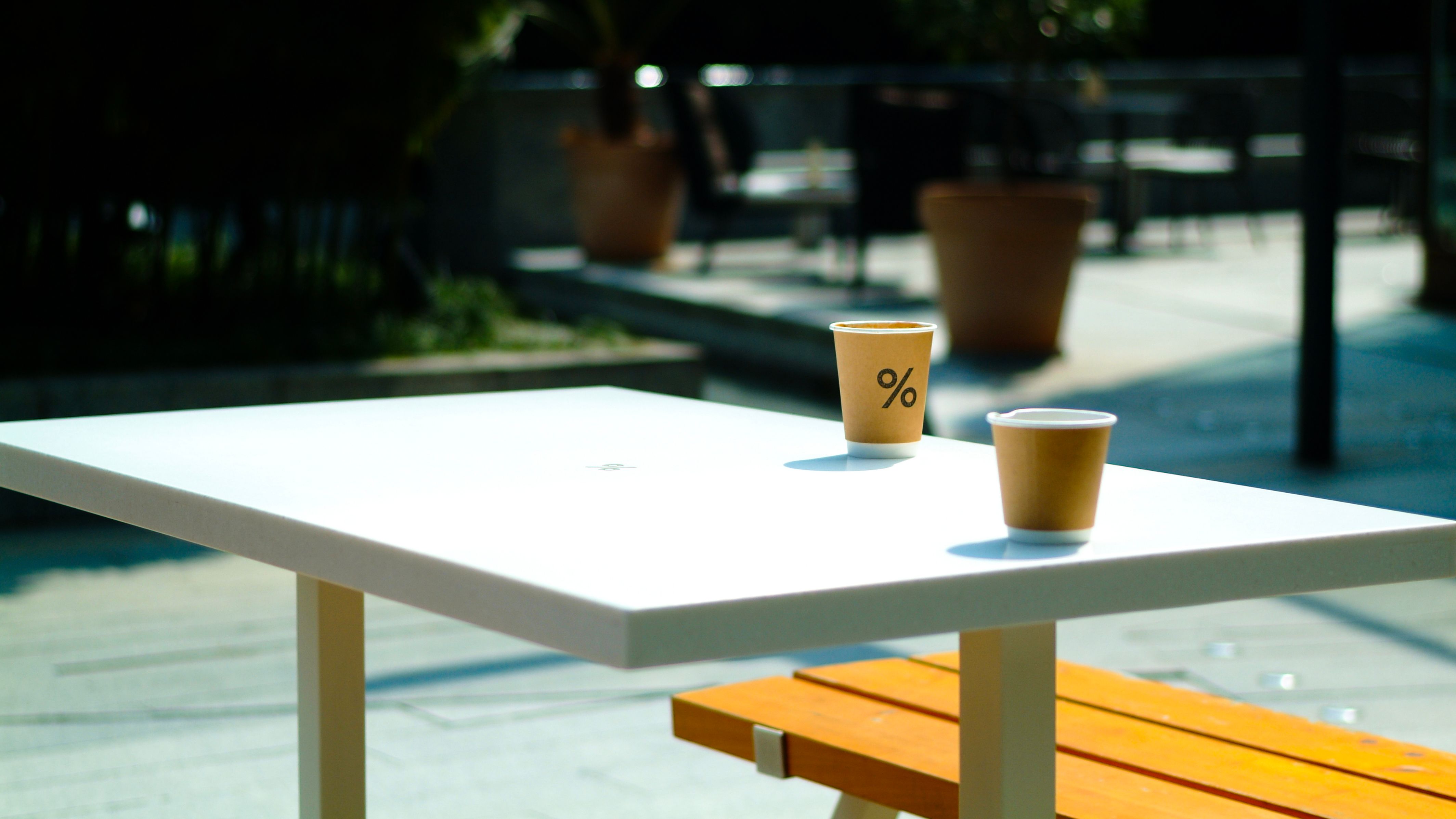 A sunny outdoor cafe table with two disposable cups, perfect for lifestyle themes.