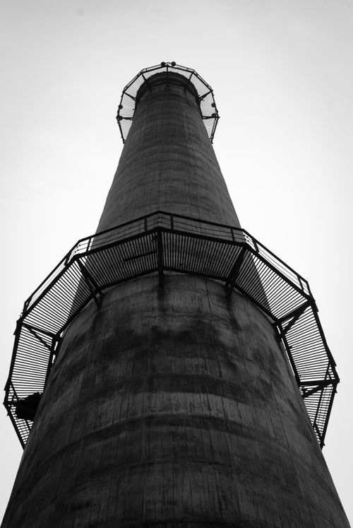 Free Low-angle shot of a towering industrial lighthouse in black and white, showcasing its architectural grandeur. Stock Photo