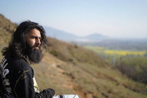 Free A thoughtful man with a beard gazes over a scenic hill landscape, capturing a serene moment. Stock Photo