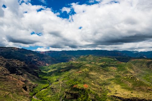 Free Stunning aerial photograph capturing a lush valley surrounded by majestic mountains under a vibrant sky. Stock Photo