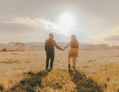 Couple Walking on a Meadow and Holding Hands 