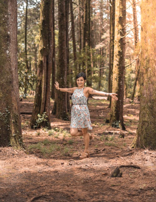 Woman Wearing a Dress with a Floral Pattern Standing in a Forest 