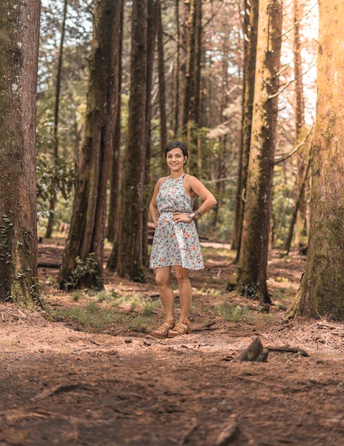 Woman Wearing a Floral Dress Standing in a Forest 