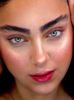 Detailed close-up portrait of a woman with striking green eyes and bold makeup.