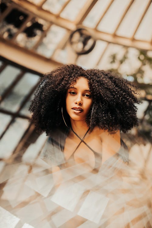 Young Woman with Afro Hair Posing in a Building with a Glass Dome 