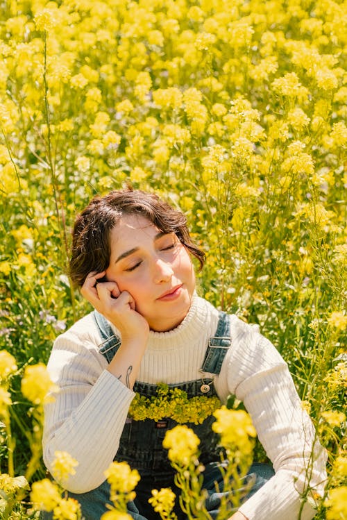 一个女人在黄色的花田里摆姿势