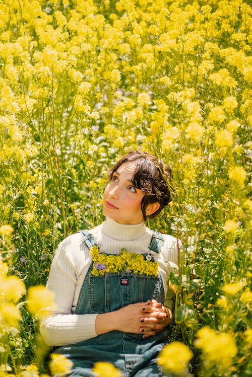 Портрет молодой женщины, сидящей в поле желтых цветов