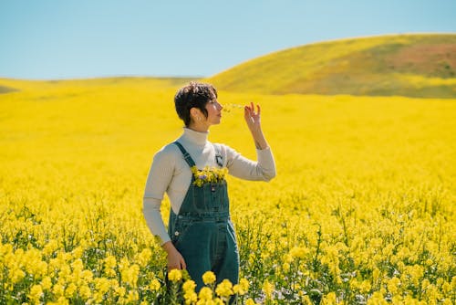 広大な黄色い花の野原でポーズをとる若い女性