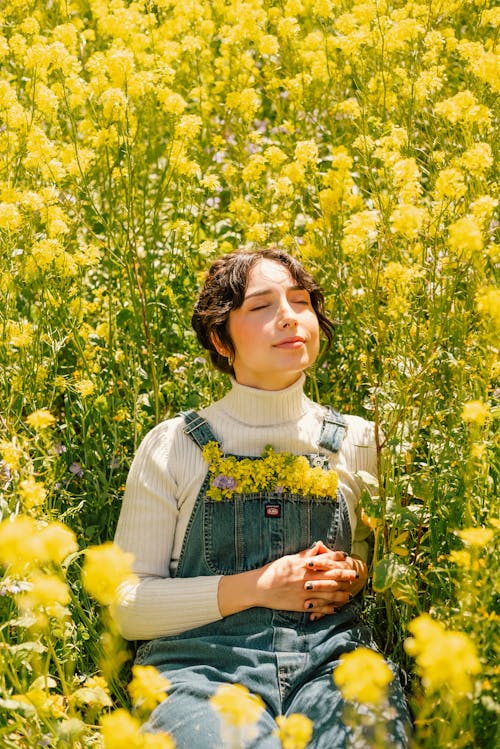黄色い花畑に座る若い女性