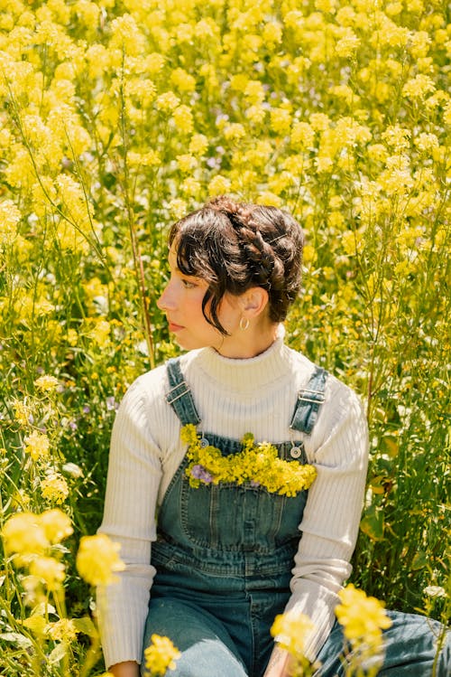 Женщина, сидящая в поле желтых цветов