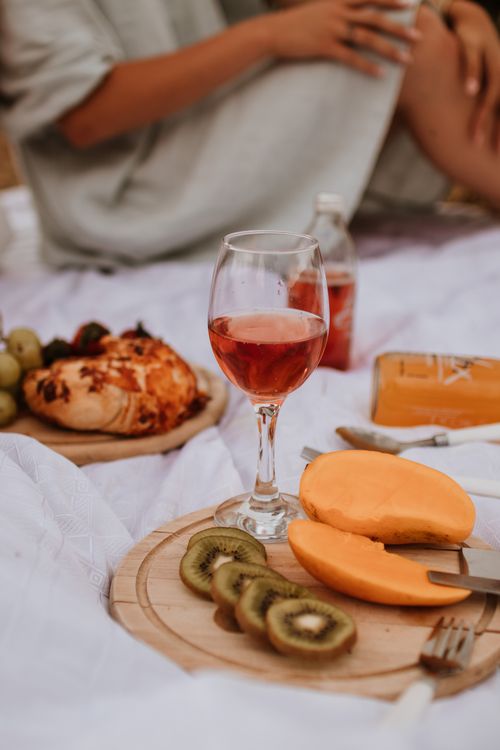 Free A cozy outdoor picnic scene with wine, fresh fruits, and pastries on a blanket. Stock Photo